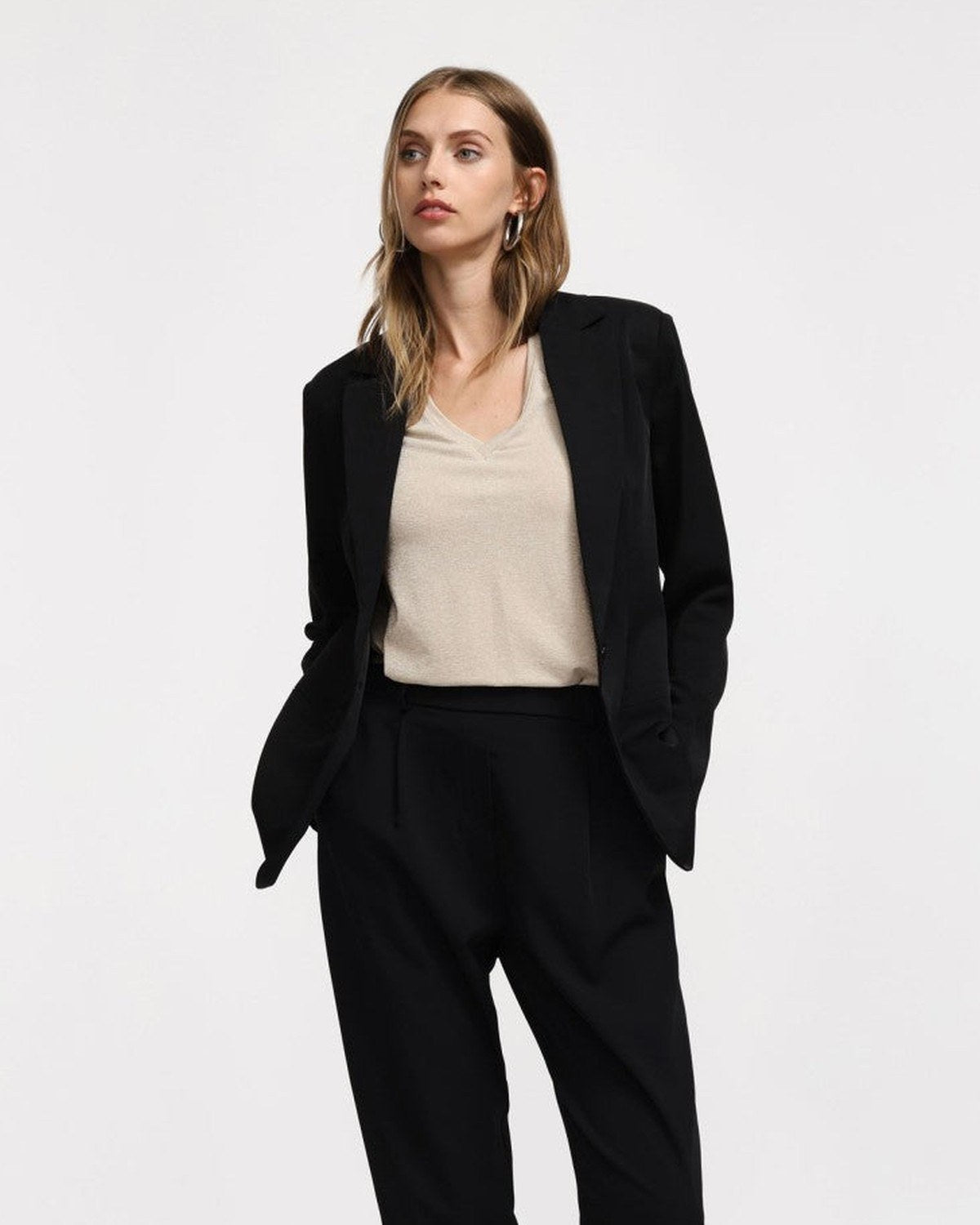 Tailleur femme noir Please porté avec un top beige
